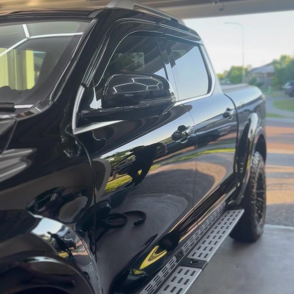 Black ute with a deep gloss finish, sunset sky reflected in the door