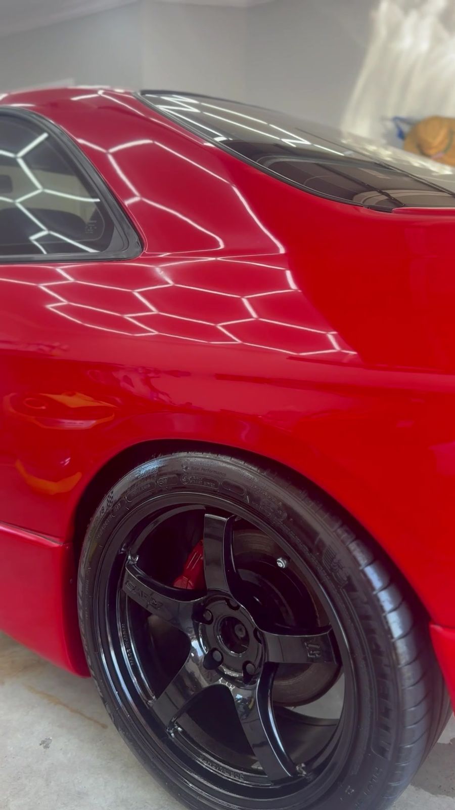 Black alloy wheel and tyre on a red car, cleaned and dressed